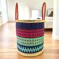 Open laundry basket with a patterned weave, open top, leather handles visible