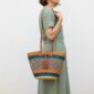 Handwoven Bolga shoulder bag with leather handles and tassel in teal, tan and natural stripes.