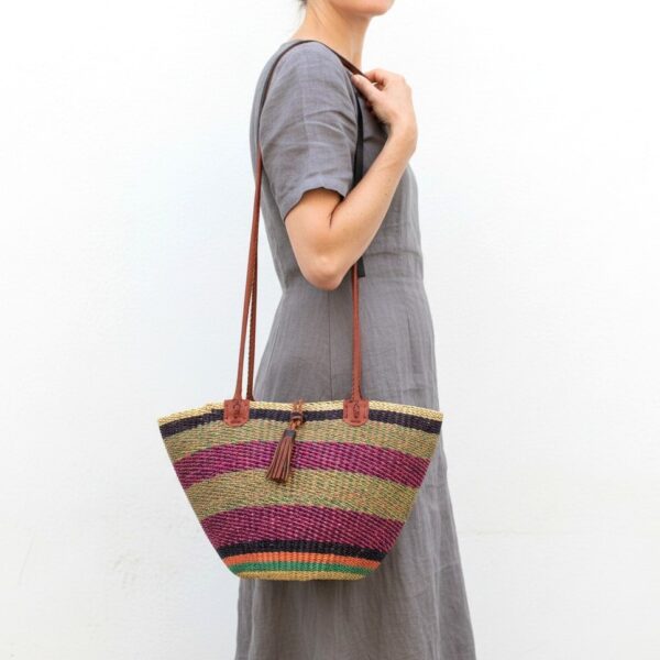 Handcrafted African Bolga shoulder bag with striped woven design, leather handles and tassel accent.