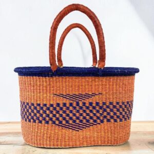 Oval woven basket with leather handles photographed against a neutral background.