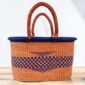 Oval woven basket with leather handles photographed against a neutral background.