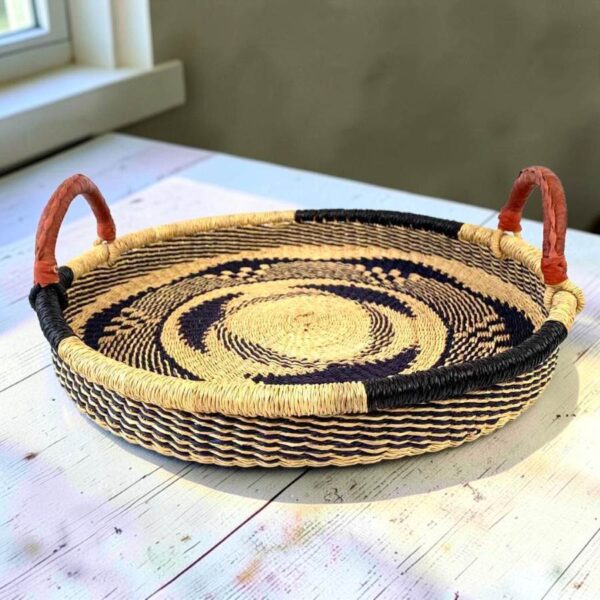 Bolga tray with leather handles styled on a wooden table by a window