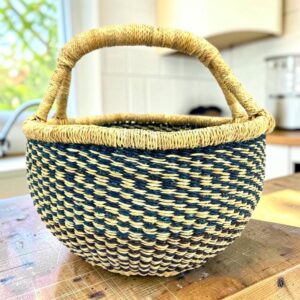 a small round african basket with a vegan handle in green and natural colours