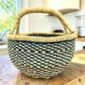 a small round african basket with a vegan handle in green and natural colours
