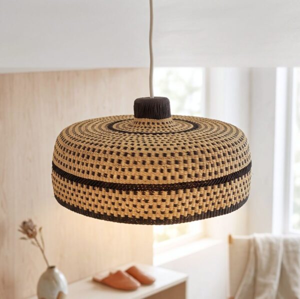 Woven bolga lampshade hanging over a bedside table, natural straw with a dark brown base band