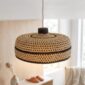 Woven bolga lampshade hanging over a bedside table, natural straw with a dark brown base band