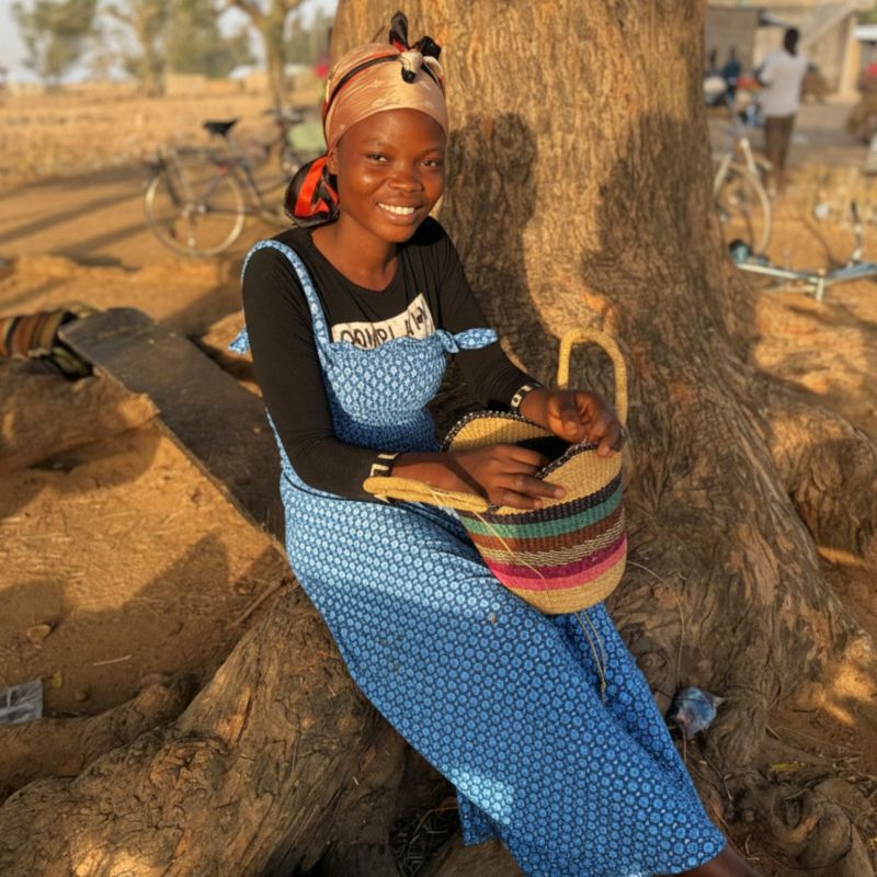 Bolga basket weaver sitting with a handwoven basket in Bolgatanga, Northern Ghana