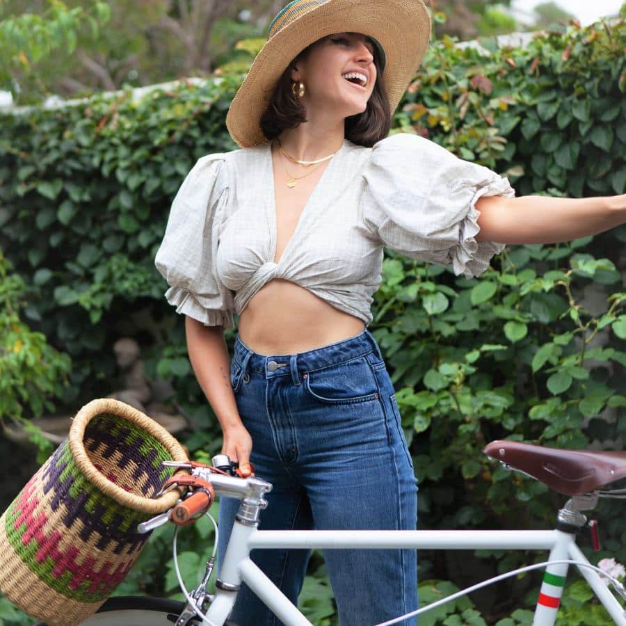 a woven bicycle basket attached to a bike, with a woman standing in front of it