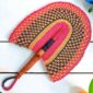 Woven Bolga hand fan in pink and black with a leather-wrapped handle