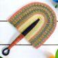 Woven Bolga hand fan in pink and natural with a leather-wrapped handle