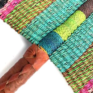 Close-up of the weave and leather handle on the pink, olive and teal Bolga fan