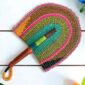 Woven Bolga hand fan in pink, olive and teal with a leather-wrapped handle