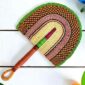 Woven Bolga hand fan in orange and pink with a leather-wrapped handle