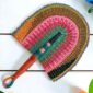 Woven Bolga hand fan in pink, teal and orange with a leather-wrapped handle