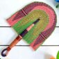 Woven Bolga hand fan in pink and green with a leather-wrapped handle