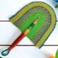 Woven Bolga hand fan in green and teal with a leather-wrapped handle