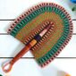 Woven Bolga hand fan in green and orange with a leather-wrapped handle
