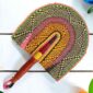 Woven Bolga hand fan in pink and orange with a leather-wrapped handle