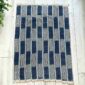 Indigo cotton cloth with solid and pinstriped panels, laid flat on a timber floor beside a plant