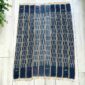 Deep blue cotton cloth with columns of pale dashes, laid flat on a timber floor beside a plant