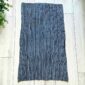 Deep indigo cotton cloth with fine pale pinstripes, laid flat on a timber floor beside a plant
