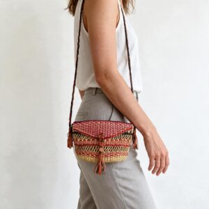 Woven mini Bolga shoulder bag in red and purple elephant grass, worn on the shoulder with a plaited leather strap