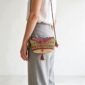 Woven mini Bolga shoulder bag in purple, pink, and green elephant grass, worn on the shoulder with a plaited leather strap