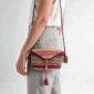 Woven mini Bolga shoulder bag in pink and purple elephant grass, worn on the shoulder with a plaited leather strap