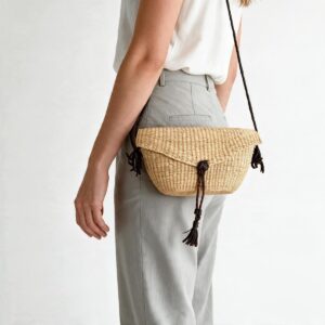 Woven mini Bolga shoulder bag in natural undyed elephant grass, worn on the shoulder with a plaited leather strap