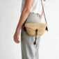 Woven mini Bolga shoulder bag in natural undyed elephant grass, worn on the shoulder with a plaited leather strap