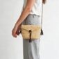Woven mini Bolga shoulder bag in natural undyed elephant grass, worn on the shoulder with a plaited leather strap