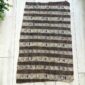 Medium mudcloth in dark and light bands of geometric motifs, laid on a timber surface with green leaves