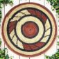 Woven raffia rust, black and natural Burkina platter with a swirl pattern, on white timber with greenery
