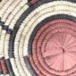 Close-up of the coiled raffia weave and centre of the rust, black and natural Burkina platter with a block pattern
