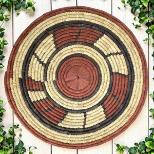 Woven raffia rust, black and natural Burkina platter with a block pattern, on white timber with greenery