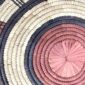 Close-up of the coiled raffia weave and centre of the rust, black and natural Burkina platter with a concentric pattern