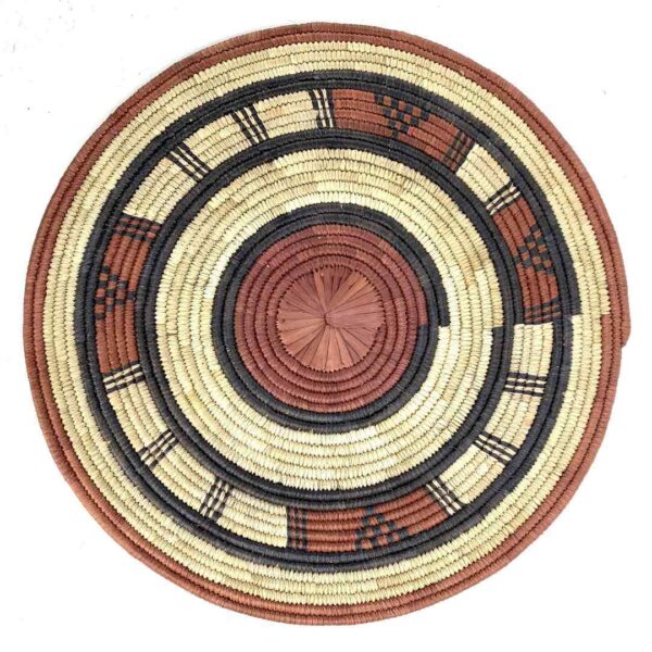 bashiri-placemat-183-flourish-african-platter-raffia-3 Full view of the rust, black and natural Burkina platter with a concentric pattern on a white background