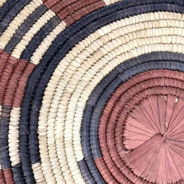 bashiri-placemat-185-tranquil-burkina-platter-handwoven-2 Close-up of the coiled raffia weave and centre of the rust, black and natural Burkina platter with a band pattern
