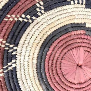 Close-up of the coiled raffia weave and centre of the rust, black and natural Burkina platter with a zigzag pattern