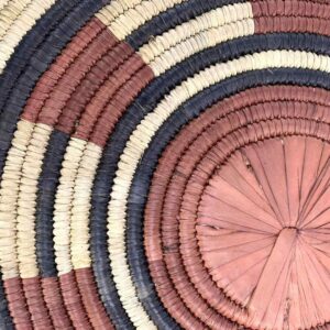 Close-up of the coiled raffia weave and centre of the rust, black and natural Burkina platter with a segment pattern