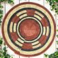 Woven raffia rust, black and natural Burkina platter with a segment pattern, on white timber with greenery