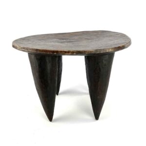 Front view of the dark hardwood Senufo stool with an oval seat and four tapered legs on a white background