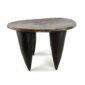 Front view of the dark hardwood Senufo stool with an oval seat and four tapered legs on a white background