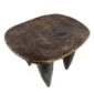 Angled view of the carved seat of the dark hardwood Senufo stool with an oval seat and four tapered legs