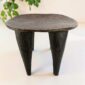Dark hardwood Senufo stool with a rounded square seat, styled beside a plant
