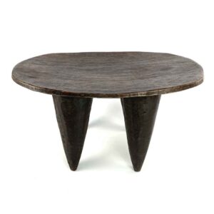 Front view of the low dark hardwood Senufo stool with a wide, elongated seat on a white background