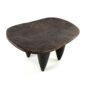 Angled view of the carved seat of the low dark hardwood Senufo stool with a wide, elongated seat