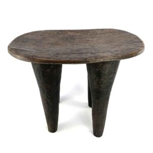 Front view of the tall dark hardwood Senufo stool with four long tapered legs on a white background