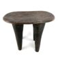 Front view of the tall dark hardwood Senufo stool with four long tapered legs on a white background