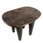 Angled view of the carved seat of the tall dark hardwood Senufo stool with four long tapered legs